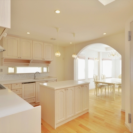 ステンドガラスの室内ドアの先にあるオーダーキッチン、曲線を描いた開口の先には洋館のようなダイニングがあります