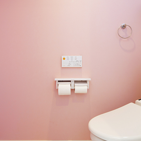 淡いピンクの壁紙が可愛らしいトイレ