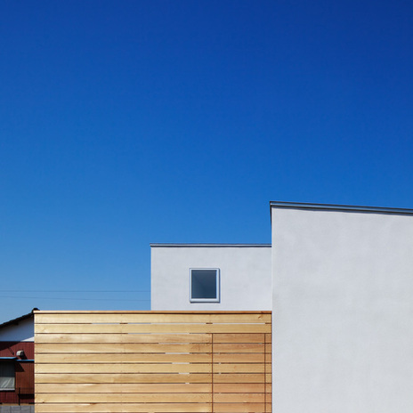 モルタル下地吹付塗装の継ぎ目のない外壁とレッドシダーの目隠し塀