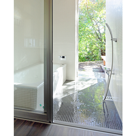 緑の庭につながる白いホーローのバスタブの浴室