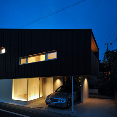 家の灯りと黒壁のコントラストが美しい夜の外観