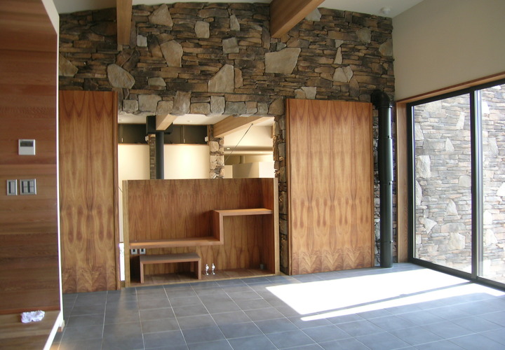 木目が美しい扉を開けると吹き抜けのリビングに繋がる