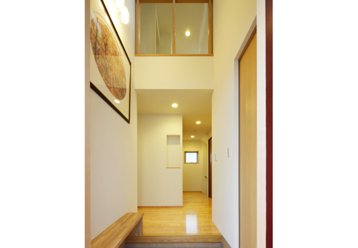 木のベンチを設置した吹き抜けの玄関