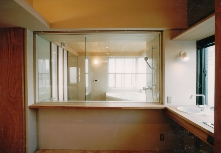 バスルームのガラス張りから明るい光が差し込む洗面スペース