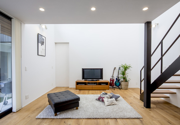 吹き抜けのあるリビングは明るく開放的、趣味のギターもインテリアのアクセントに