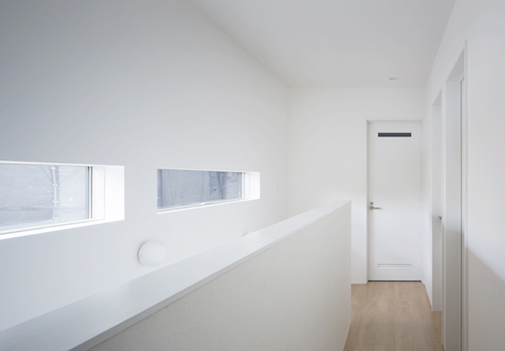 白い空間に日差しを取り込む階段横の窓