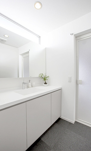 高い位置の窓から十分な明るさを確保した白い洗面所