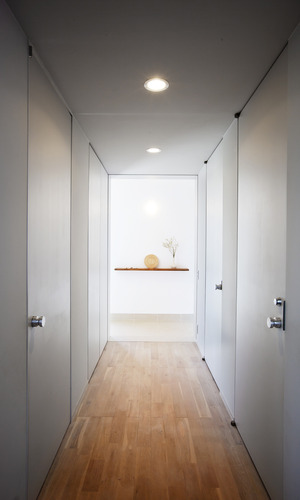 淡いグレーで統一された、全体的に光を絞ったトンネルのような廊下