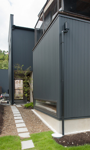 木々の緑に溶け込んだ、黒色ガルバニウムの外壁