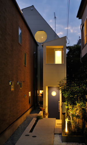 旗竿上の敷地に建つ、大きな丸窓と青い玄関の小さい丸窓が印象的な外観