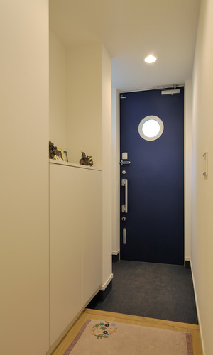 外の気配を感じられる、丸い明かり窓がキュートな青い玄関ドア