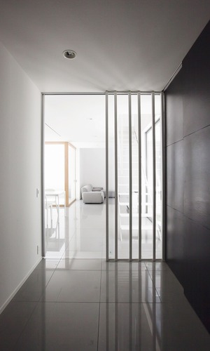 光を抑えた玄関アプローチを抜けると光と緑に囲まれるＬＤＫにたどり着く、ガラスの引き戸と格子を採用した玄関ホール