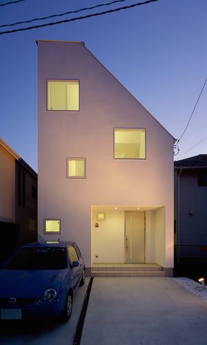 閑静な住宅街に、潔い白さ放つ外壁とランダムな配置の窓から穏やかな光が溢れる外観夜景