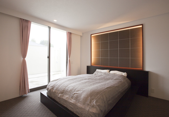 窓の先にはプライベートテラスが広がり、ベッドボード廻りを間接照明で彩った主寝室