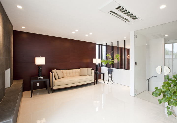 ソファーの背面の壁をガラス越しに玄関ホールまで続けることで、視覚的な広がりを感じられるリビング