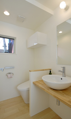 白木と白を基調にした、トイレと洗面所をユニットさせ広さを強調した空間