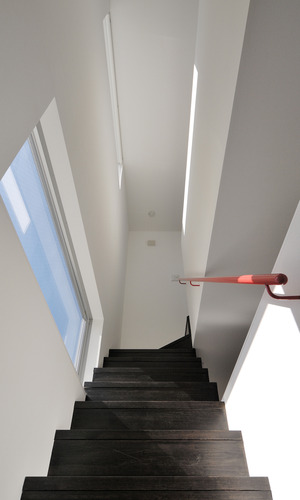 赤い手摺が、各階の家族の空間をつなげていく階段
