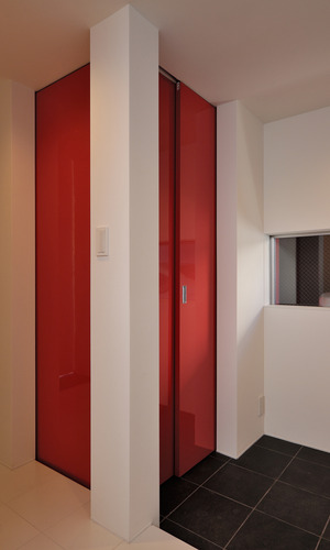 白と黒のタイルの床材に、この家のシンボルカラーの赤色の扉が個性的な玄関ホール