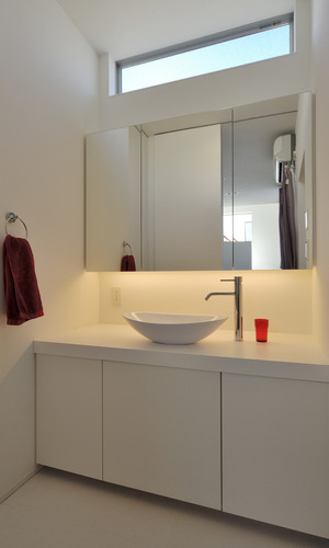 上部に設置された窓から光を取り込む、シンプルな洗面所周り