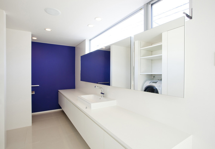 白の空間に彩度の高い青色の壁が、生活感を感じさせない洗面所