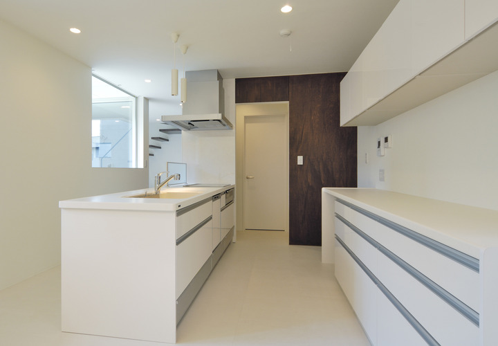 白を基調に茶色をポイントカラーにし、壁で隔たることなく見通しのよいキッチン