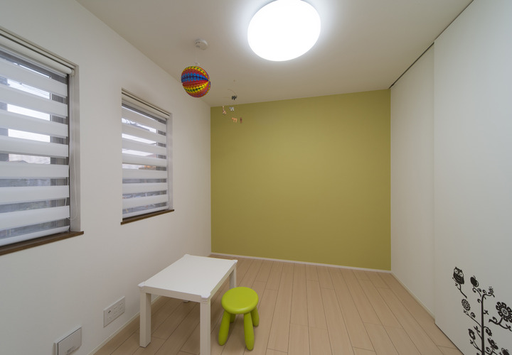 若草色の壁と柔らかい光が入るロールカーテンが印象的な、かわいらしい子供部屋