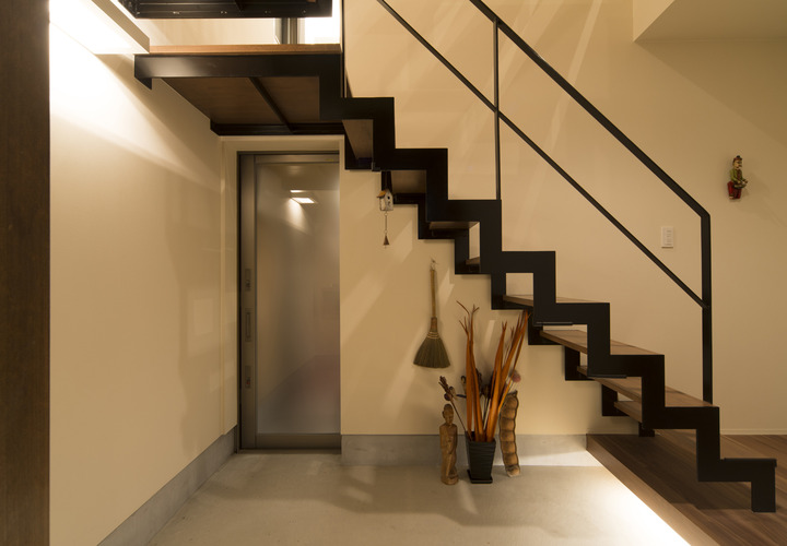 階段と玄関ドアの空間バランスがよい、アジアンテイストを含んだ玄関ホール