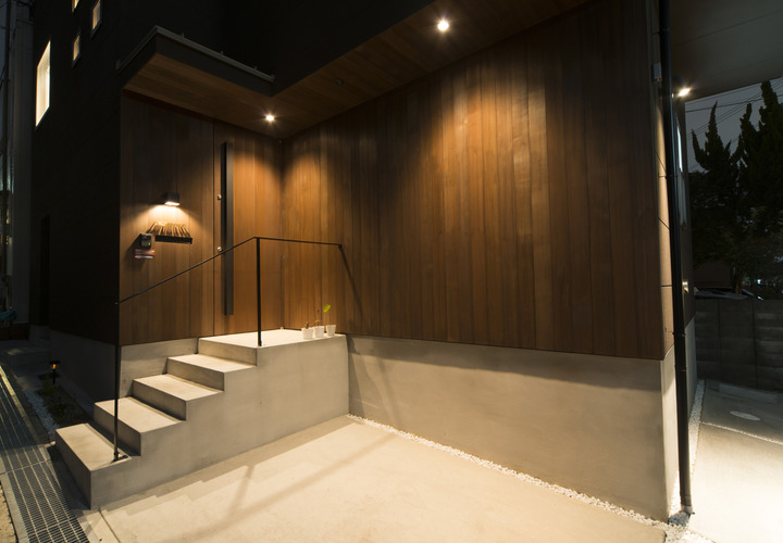 深みのある色合いの木外壁とダウンライトが、バーのような雰囲気に仕上げた玄関