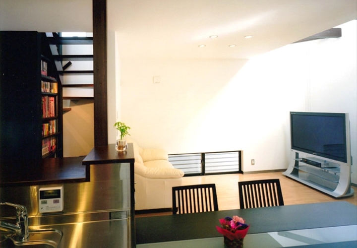 ダイニングキッチンからリビングと開放的な階段を見る