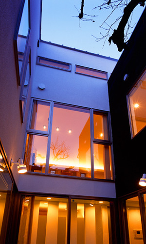 中庭から夜の灯りがもれる家を眺める