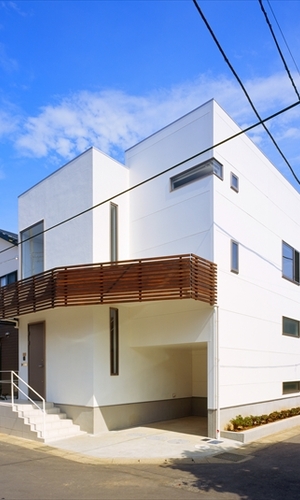 茶色のバルコニーがアクセントの白い外観