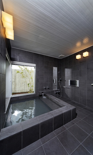 黒のタイル張りが重厚感のある、温泉が引かれた浴室