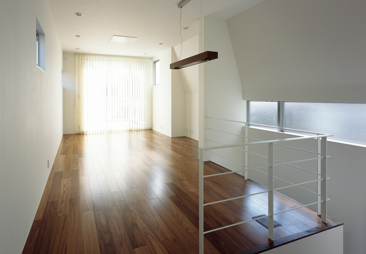 スキップフロアにより立体的に光が入る、ウォルナットのフローリングが似合う洋室