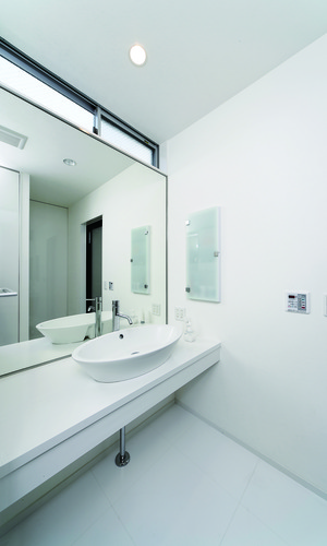 トップライトからの光と壁一面の鏡が、洗面所を広く見せる手段の一つ