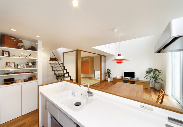 ルイスポールセンの赤い照明で個性をプラスした、清潔な白と茶色でまとめられたキッチン