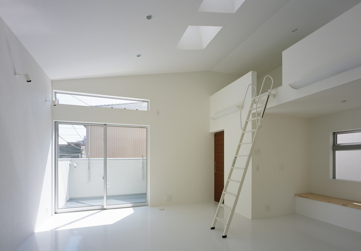 斜め天井より差し込む光が白い床に反射する、のびやかなリビング