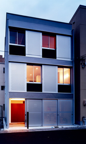 ファサードの無機質なアルミパンチングを、室内の個性的なカラーがさらに際立たせる