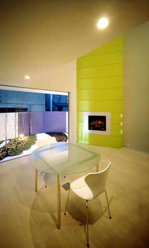 若草色の暖炉のあるリビングから設えた庭を楽しむ