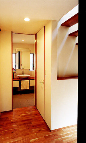 巾木・廻り縁・ドア枠を木に揃え、白い壁に「動」を取り入れた廊下