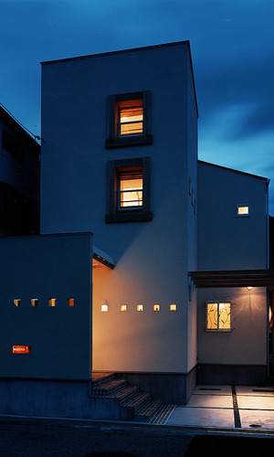 ニッチを兼ねた小さな小窓と、植物の動きを感じるアイアンの面格子が目を引く夜の外観