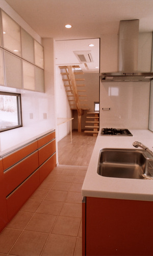 差し色のオレンジ色と、床タイルがよく似合う収納力のあるキッチン