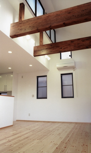 太い梁をデザインとして処理した、吹き抜けのあるリビング空間