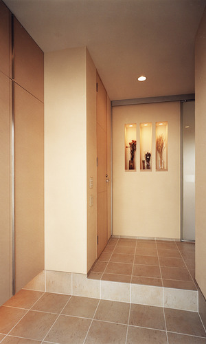 玄関とフロアラインと同じタイルを使用し、連続的な動きを出した玄関ホール