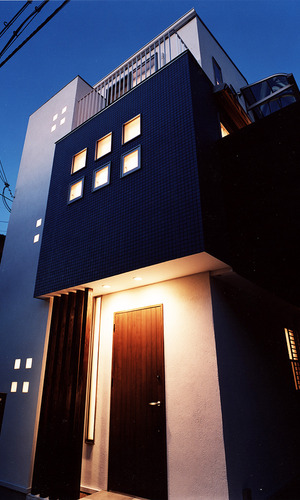 正方形の小さな窓から、建物自体が照明になったかのようにほっこり光を帯びる外観