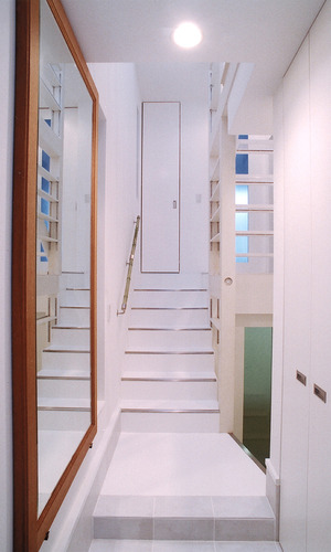 大きめの姿見を玄関に設置した、白が眩しい玄関ホール