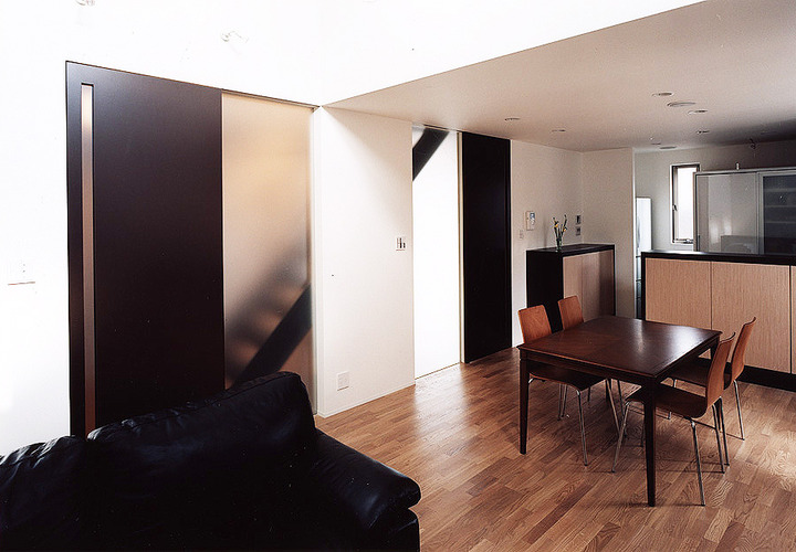 コントラストの強い白黒の色合いに差し色のように入り込む、フロストガラス壁からこぼれ落ちる光