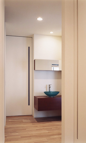 壁からスッと出てきたような洗面台に、ブルー色のガラスでできた洗面器が美しい佇まいの洗面所