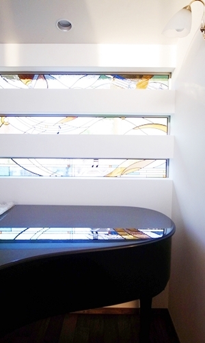 ステンドグラスが反射する漆黒のグランドピアノ