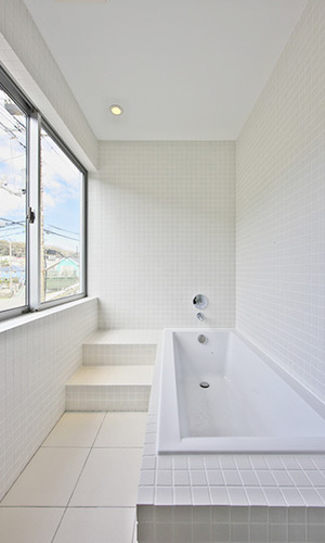 大きな窓のあるタイル張りの明るいバスルーム