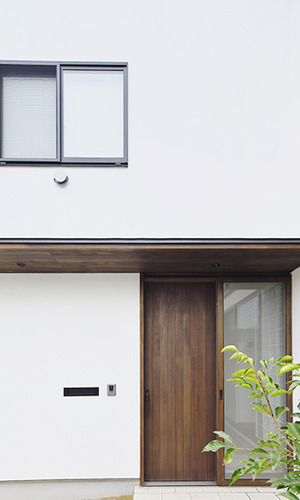 白い壁とコントラストを奏でるウッド調の玄関ドア